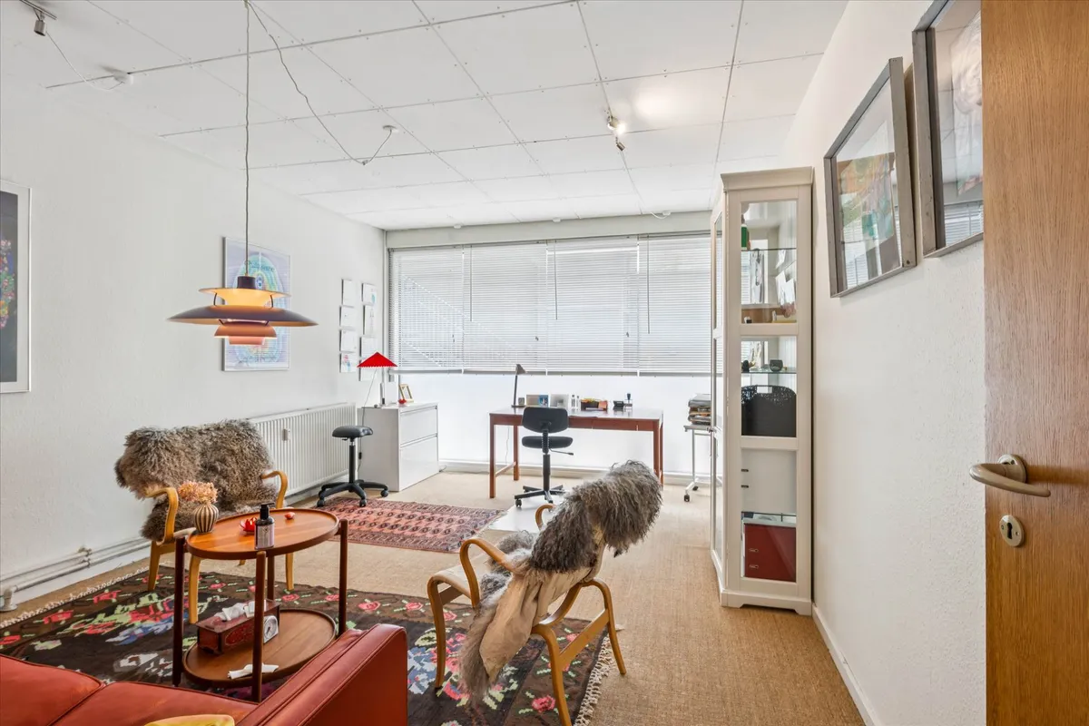 Inde i et lysestudie med hvide vægge og lofter, moderne møbler og en lysekron, der hænger fra loftet