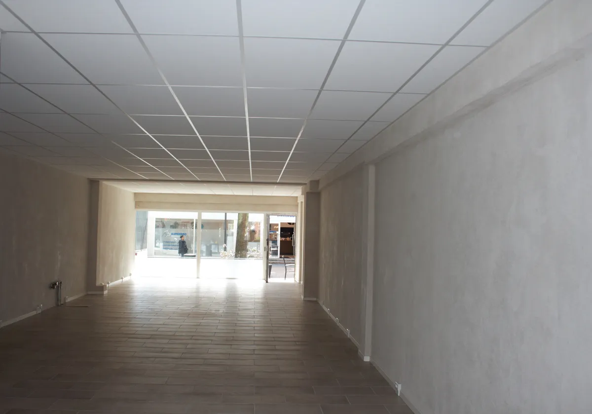 Foto af en moderne og lyse butikspassage med gulvbelægning og vægbeklædning i lyse nuancer og højt loft med hvide loftslister