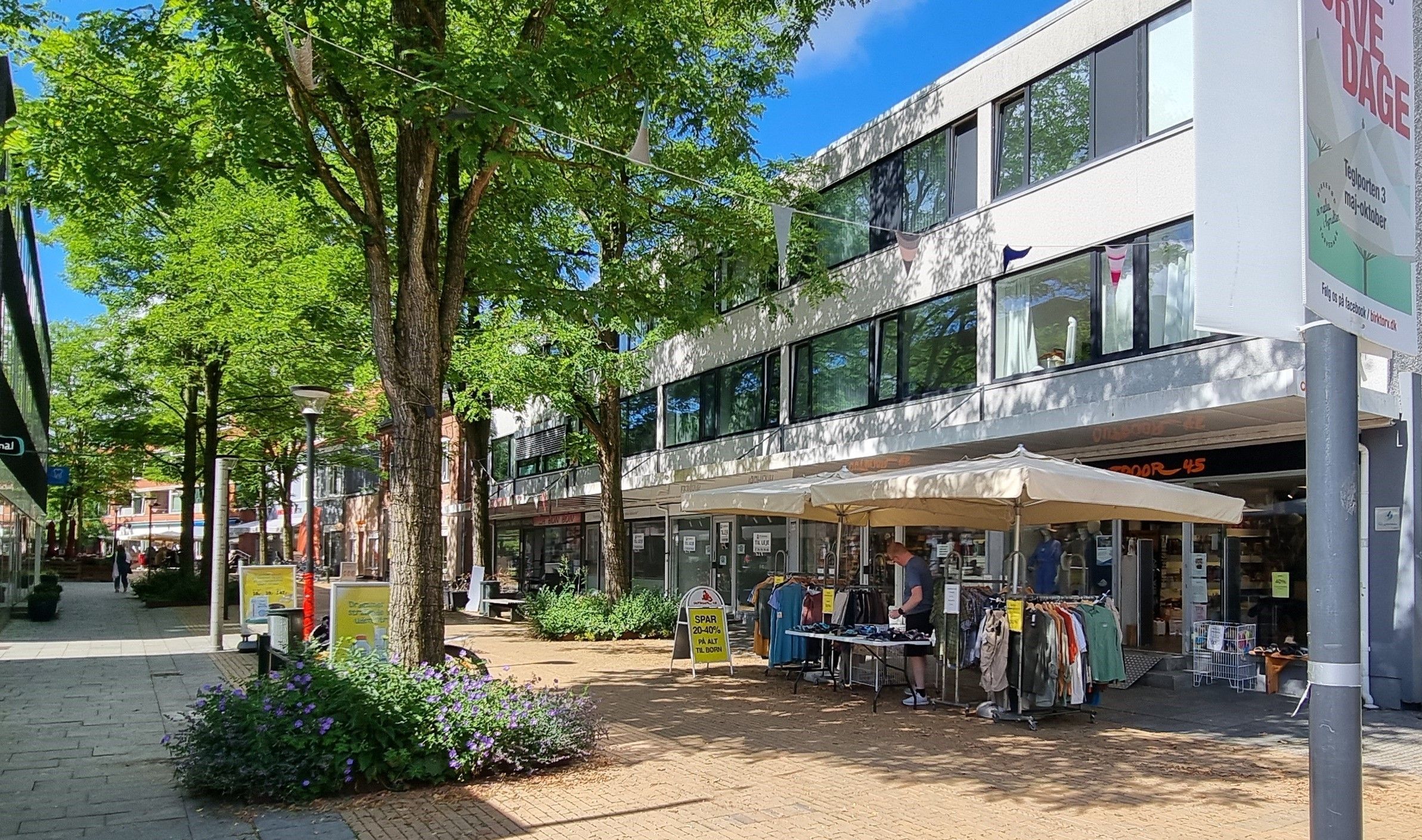 En gågade med forretninger og en mand, der sælger tøj under et paraplytæppe