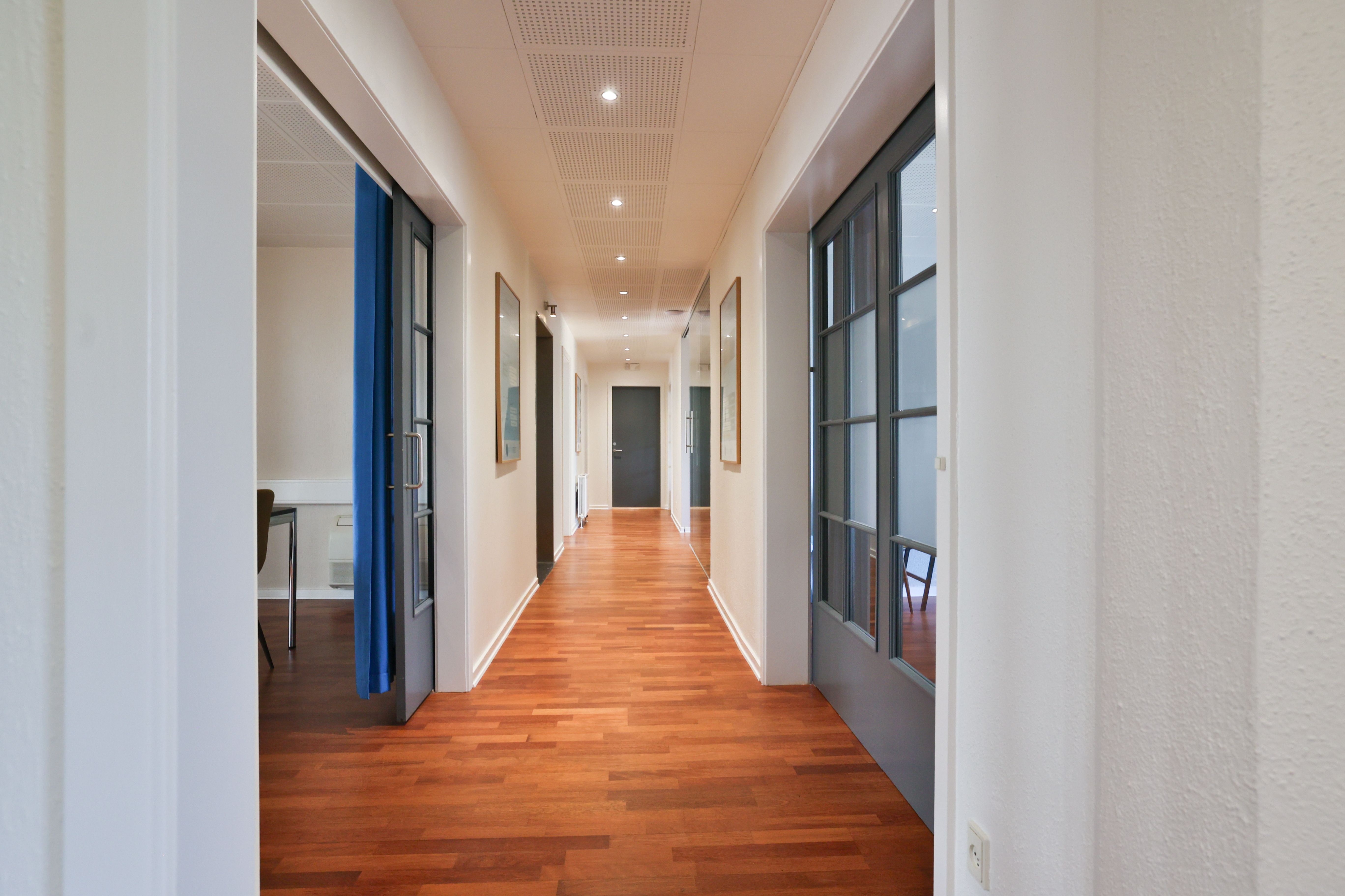 Kort og rummeligt kontor i Kontorfællesskabet Avisen i Ikast med lysegult gulv, hvide vægge og lyseblå døre