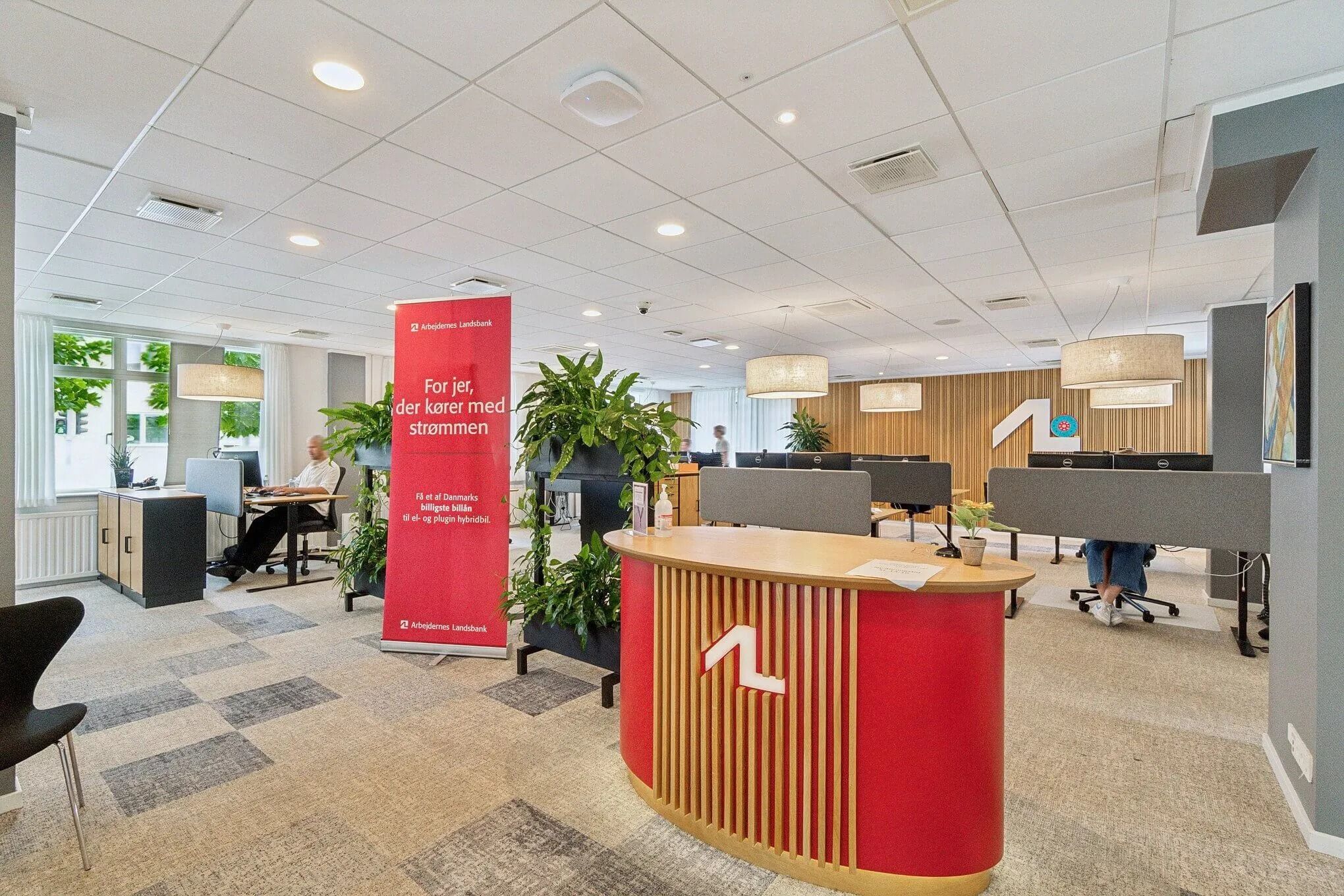 Kontor i Hvidovrevej med moderne møbler, højloft, planter og to personer i baggrunden
