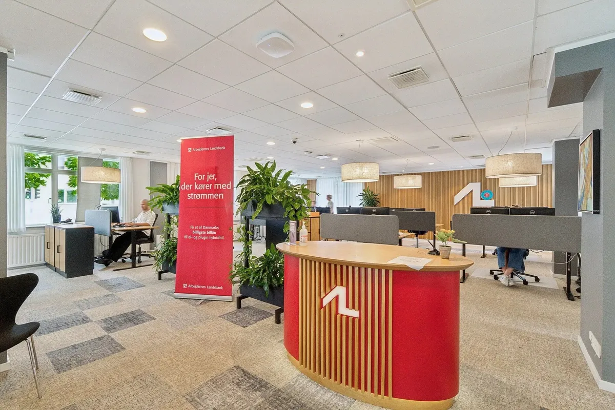Kontor i Hvidovrevej med moderne møbler, højloft, planter og to personer i baggrunden