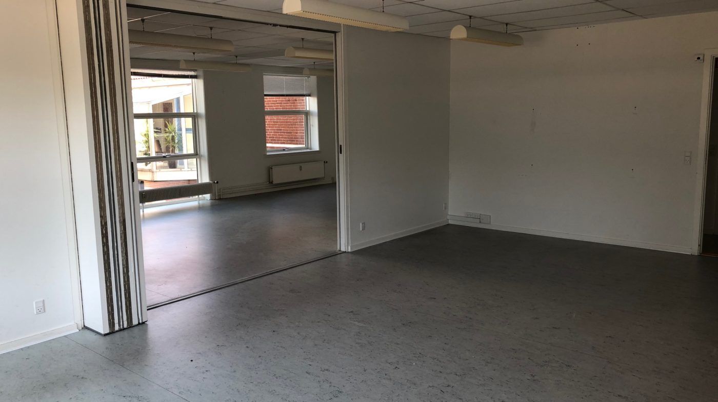 Moderne og åben kontorrum med store vinduer og hvide vægge, møbler mangler, hvide loftsbelægninger, hvide gulvbelægninger og