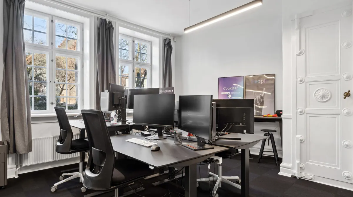 Kontor med lysevinduer og moderne udstyr som computere og skriveborde