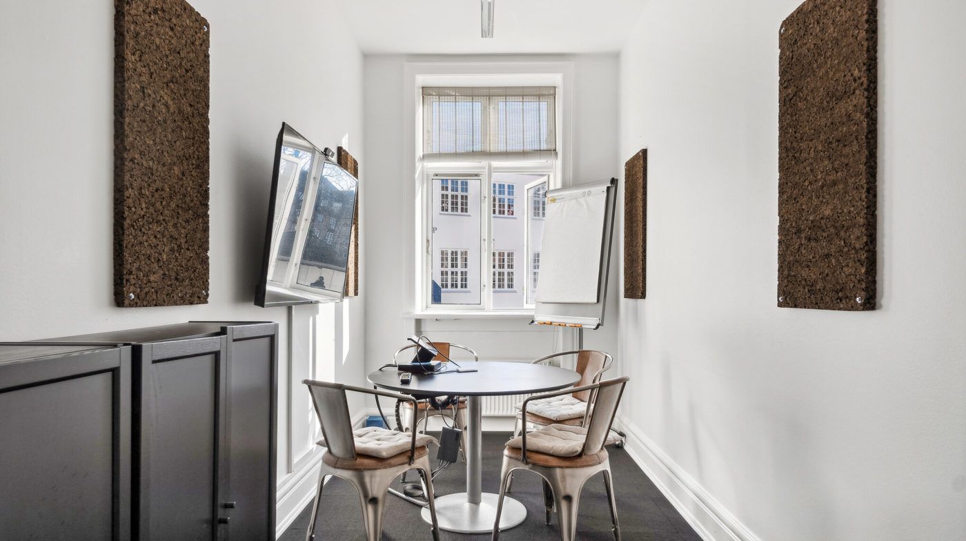 Moderne kontorlejemål med møbler, hvide vægge, runde bord og vinduer med gardiner