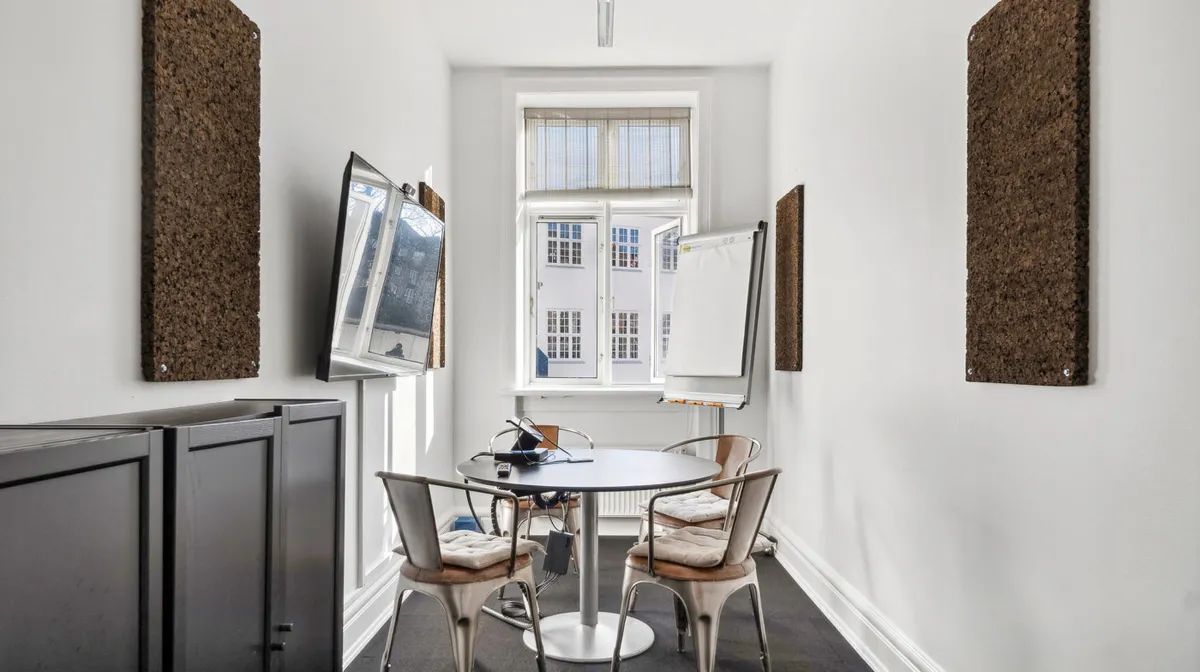 Moderne kontorlejemål med møbler, hvide vægge, runde bord og vinduer med gardiner