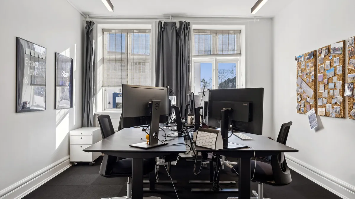 Kontor med skriveborde, højtalere, computere, mus, kabinetter og hængekøkken i Nedergade Kvarter i Odense C