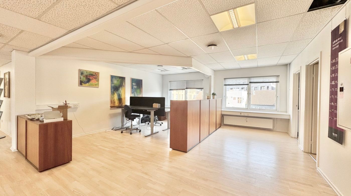 Et stort kontorlokal med moderne møbler og malerier på væggen samt en åben vinduesfront