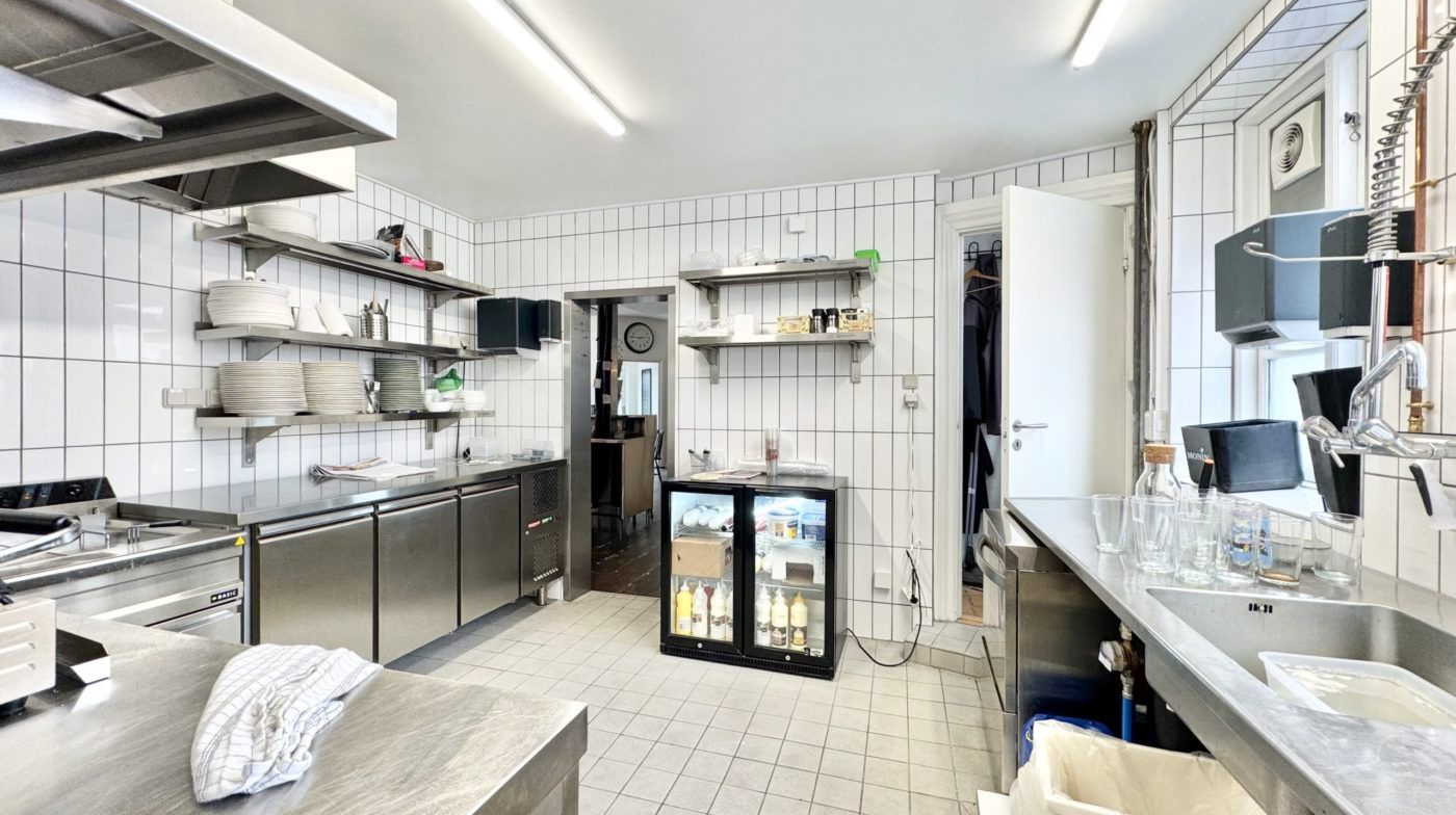 Professionelt udstyret køkken med køleskab, ovn, kogeplader, og alle nødvendige apparater til madlavning. Køkkenborde og