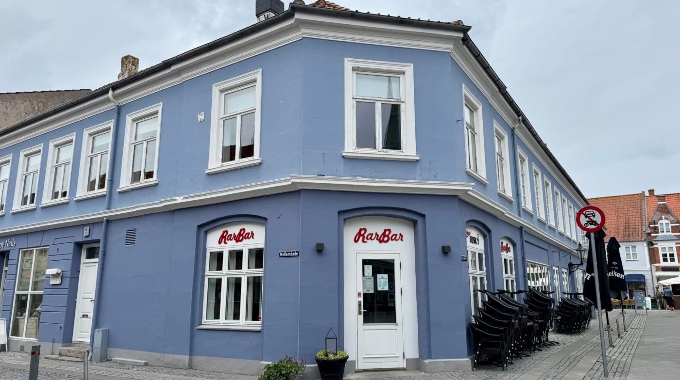 RarBar på Mellemgade i Nyborg Centrum med hvide vinduer og døre samt en række stole og parasoller udenfor.