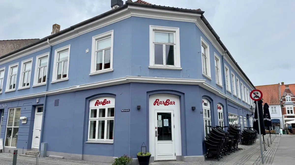 RarBar på Mellemgade i Nyborg Centrum med hvide vinduer og døre samt en række stole og parasoller udenfor.