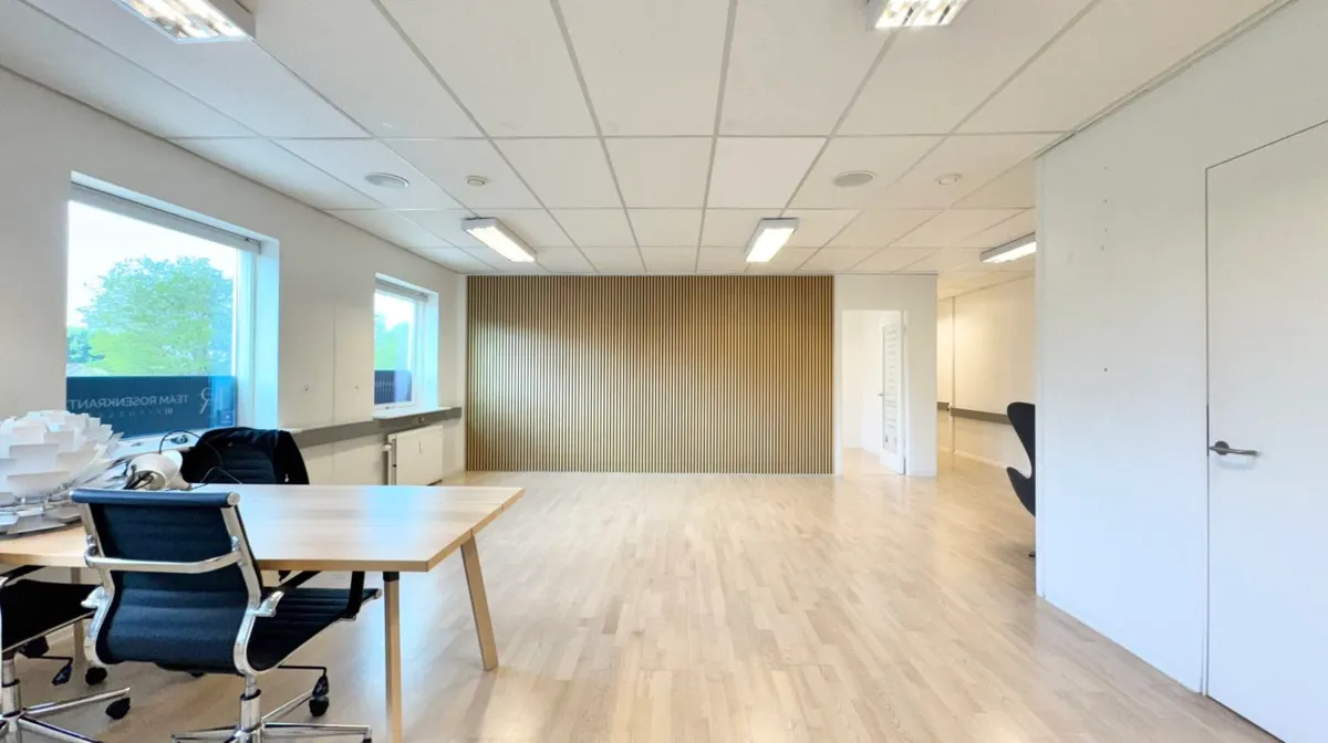 Lokaler med lyse gulve og hvide vægge, møbler, vinduer og lysekroner samt reklameskilt i hjørnet