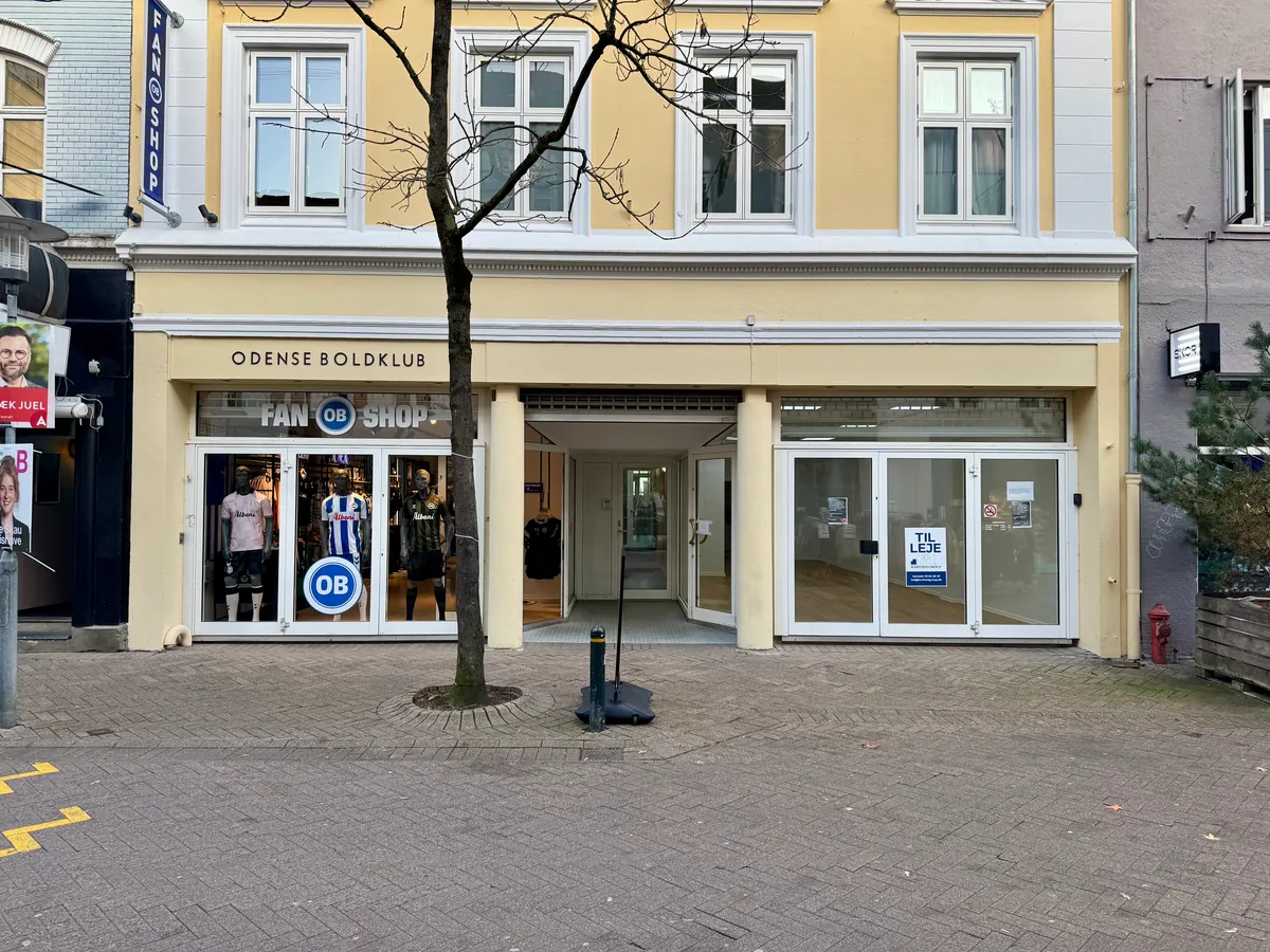 Butikslokal til leje på Kongensgade 39, Odense C. Lokale med vinduer, skilte med Odense Boldklub og OB-shop, glasdøre og tydelig vejledning til åbningstider.