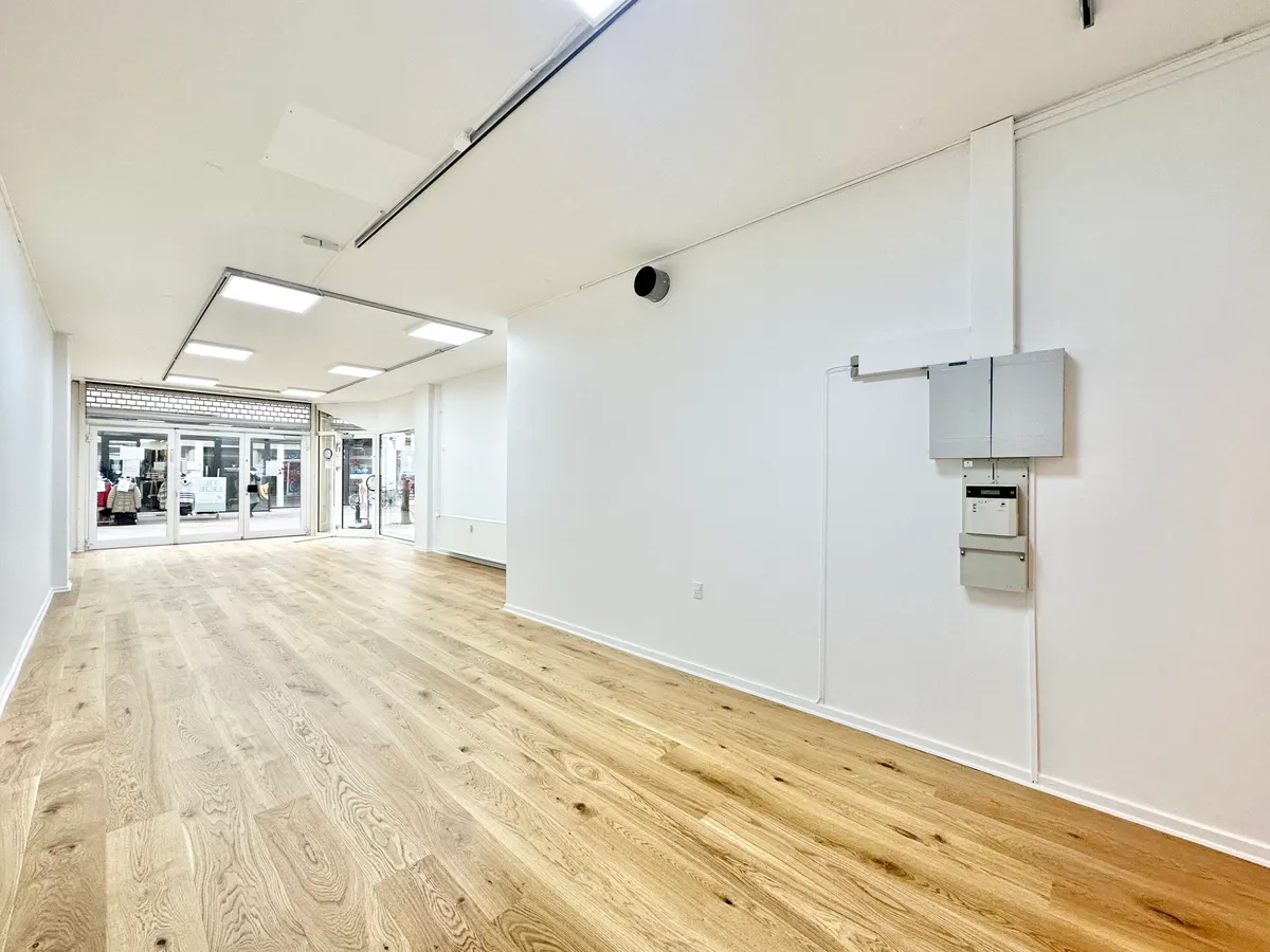 Lejlighed til leje med store vinduer, lyse lofter og trægulv. Værelset er ubeboet med to hvide vægge og en dør med elektronisk lås.