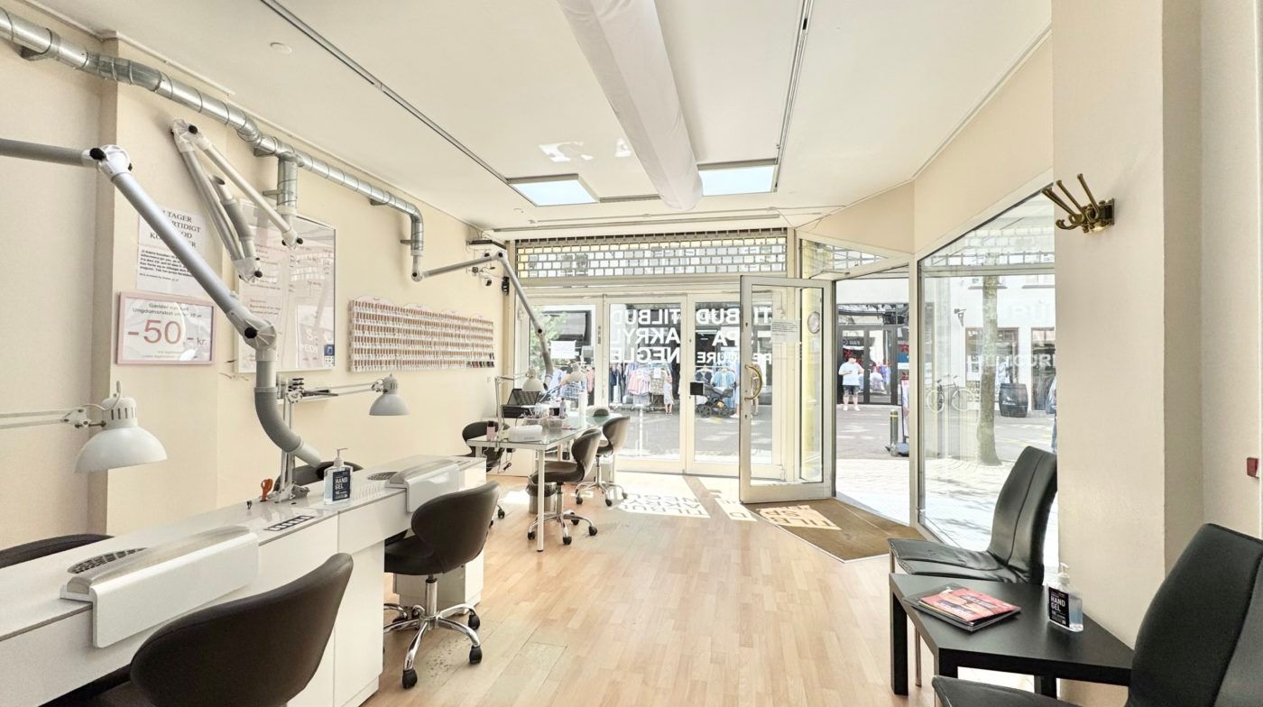 Lys stue med højloft, store vinduer og stolpeborde til leje i Odense City. Inde er der lyse trægulve og højloft med