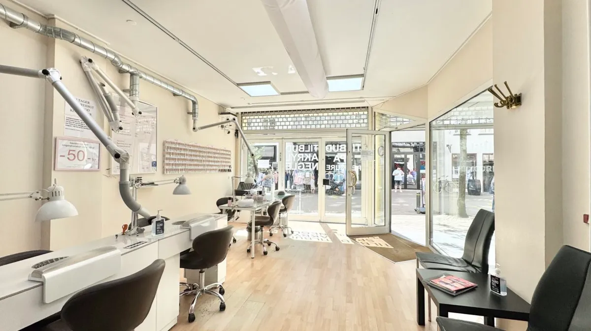 Lys stue med højloft, store vinduer og stolpeborde til leje i Odense City. Inde er der lyse trægulve og højloft med