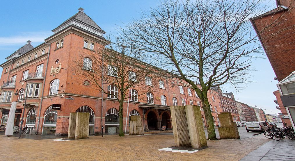 Forsiden af et stort, rød murstensbygning med flere vinduer og balkoner samt en stor indgang