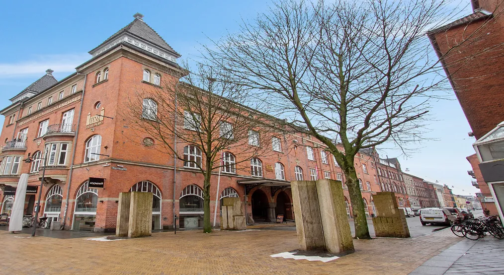 Forsiden af et stort, rød murstensbygning med flere vinduer og balkoner samt en stor indgang