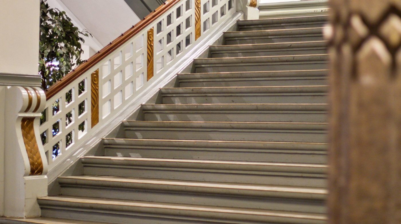 Støbejerns og træ trapper med lyse nuancer og mønstre på siderne. De er placeret indendørs i et hus og har en tydelig