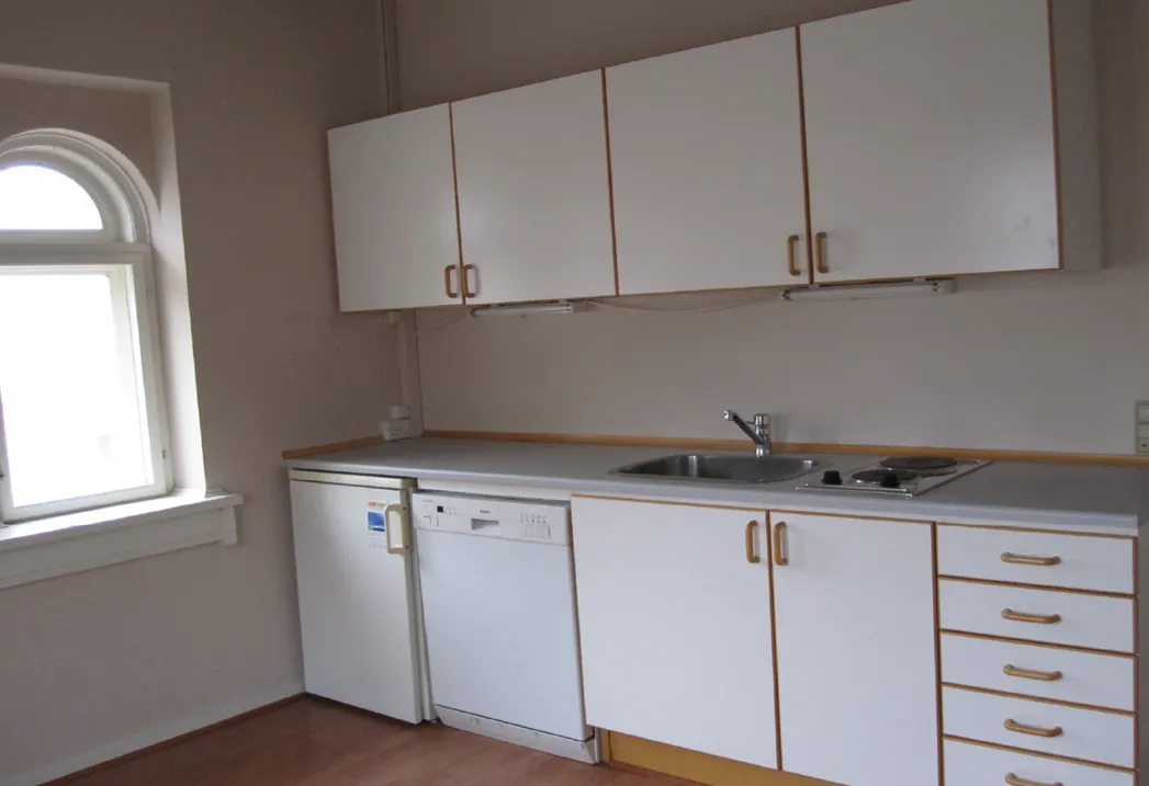 Et eksemplar af et hvidt køkken med moderne møbler og en hvid køleskab samt en hvid opvaskemaskine