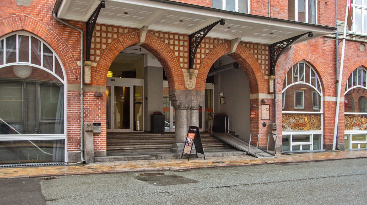 Foto af en stor rødmaurstensbygning med tre store buer. Midtbuen er døråbning. Der er flere vinduer, der er åbne. Der er en