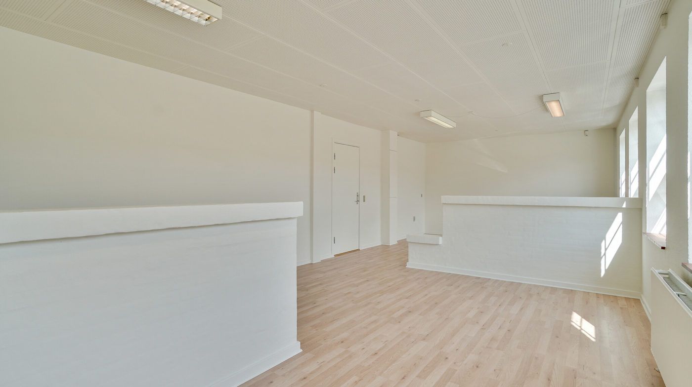 Rummelige kontorlokaler med hvide vægge og lyse trægulve. Der er lysekroner i loftet og et hvidt loft. Værelserne har hvide