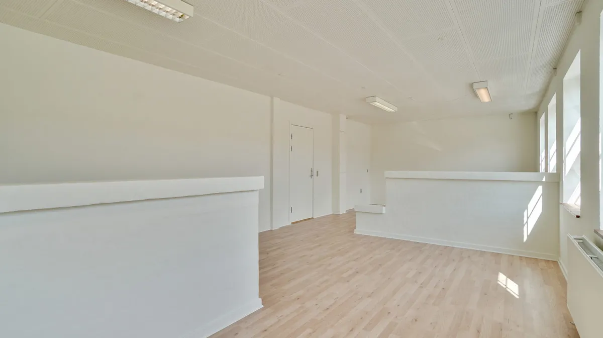 Rummelige kontorlokaler med hvide vægge og lyse trægulve. Der er lysekroner i loftet og et hvidt loft. Værelserne har hvide