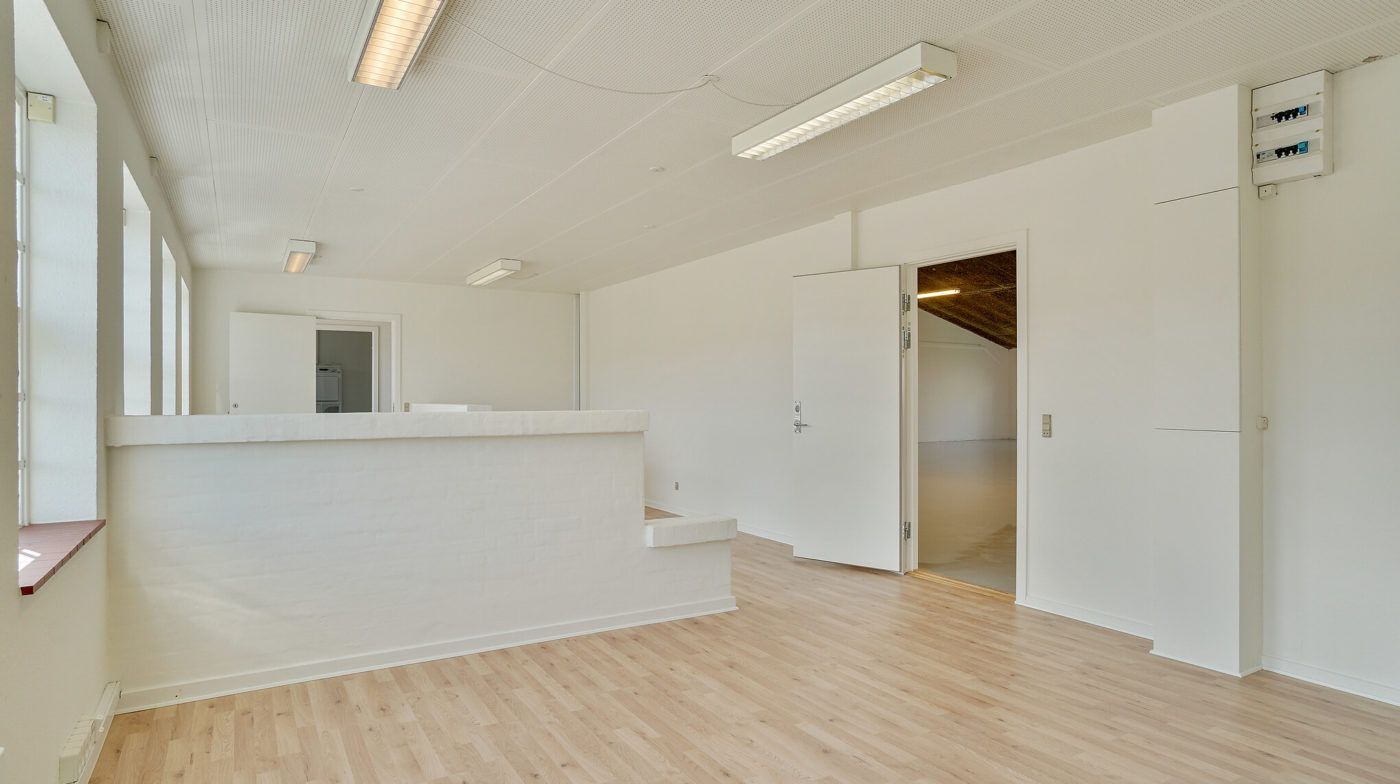 Lager med kontor i Fredericia Teknikervej med hvidmalede vægge og lyse trægulve samt åbne døre og vindueskarme