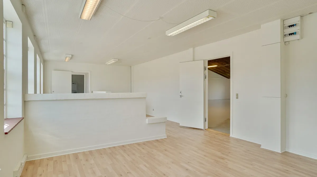 Lager med kontor i Fredericia Teknikervej med hvidmalede vægge og lyse trægulve samt åbne døre og vindueskarme