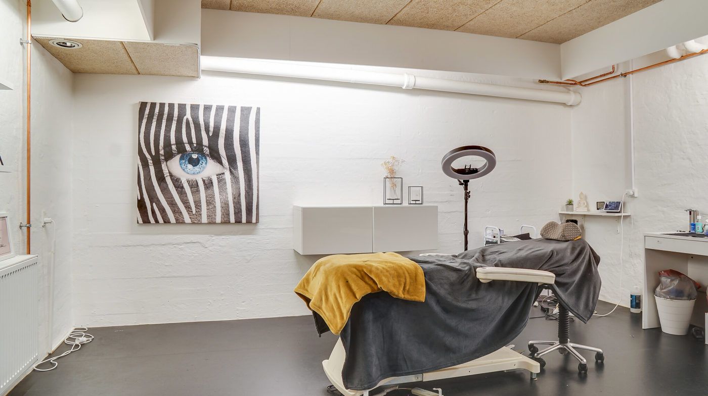 Lejlighed med senge og tøj i et lyse og rent værelse med zebrabillede på væggen og et højt lys over hovedet