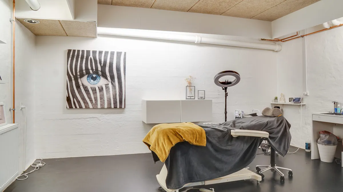 Lejlighed med senge og tøj i et lyse og rent værelse med zebrabillede på væggen og et højt lys over hovedet