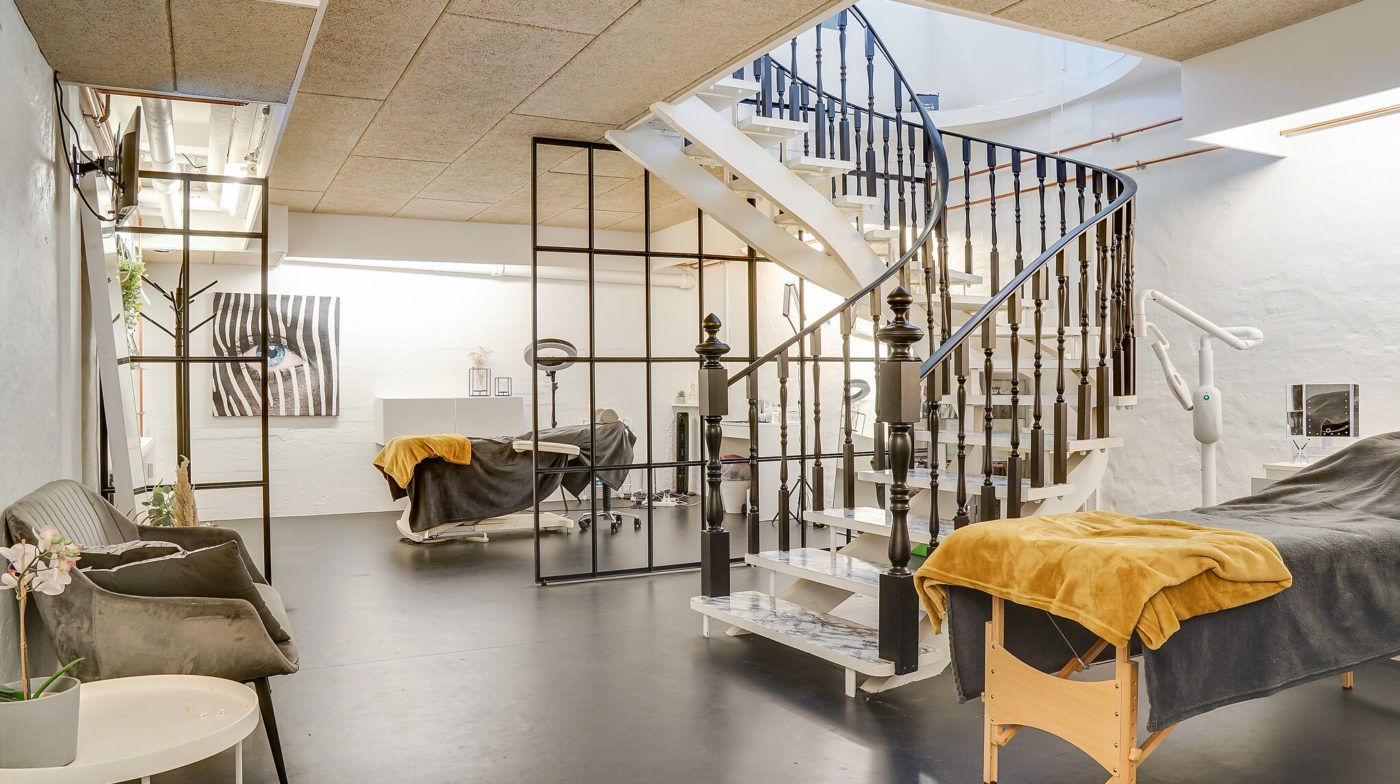 Foto af en moderne indretning med en gulvbelagt stue og sofa med blomster. Der er et stige, der fører op til et højere