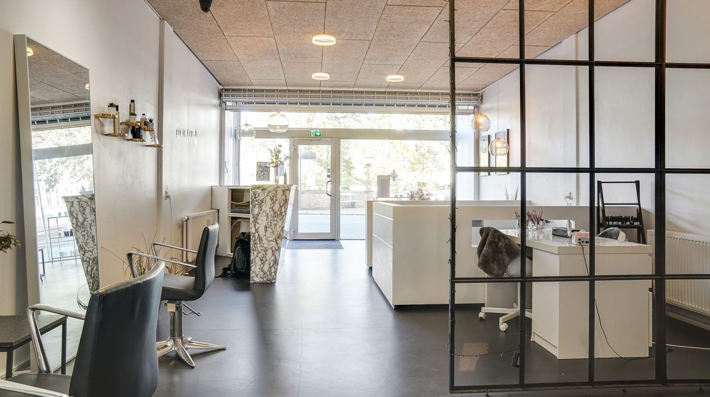 Inde i et moderne og luksuriøst frisørsalon med hvide vægge og gulv samt møbler i lyse nuancer