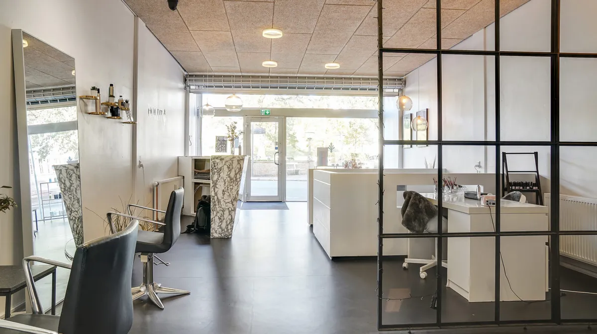 Inde i et moderne og luksuriøst frisørsalon med hvide vægge og gulv samt møbler i lyse nuancer