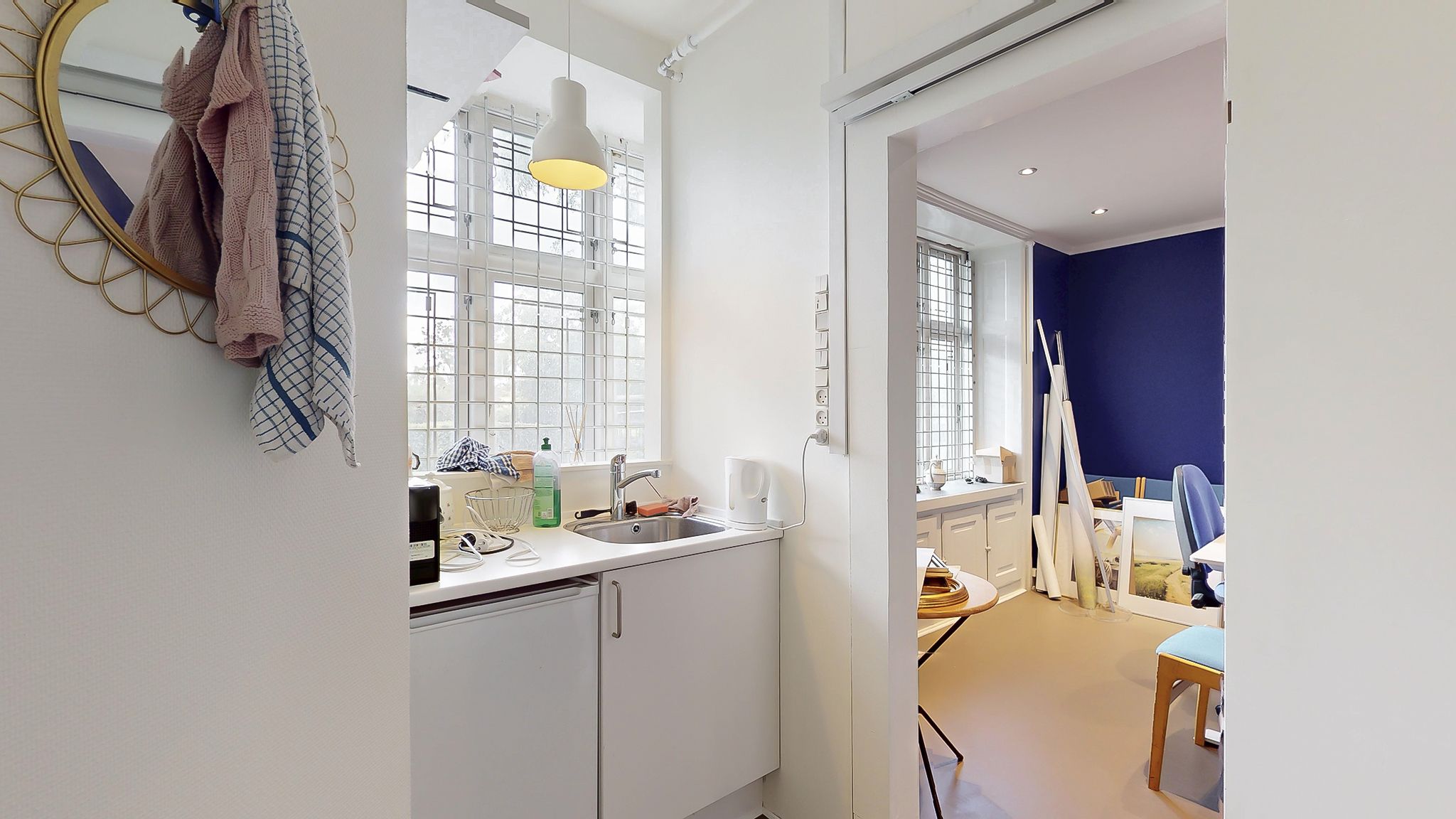 Hjørnekøkken med lyse loftsvinduer og udsigt til byen, fuldt udstyret med moderne køkkenredskaber og en stor spejl.