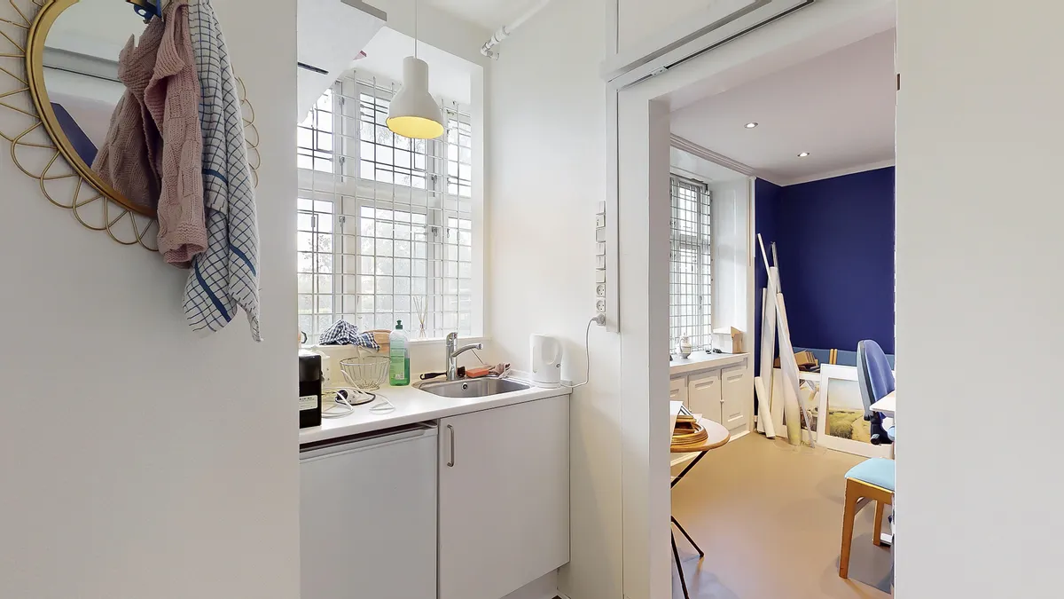 Hjørnekøkken med lyse loftsvinduer og udsigt til byen, fuldt udstyret med moderne køkkenredskaber og en stor spejl.