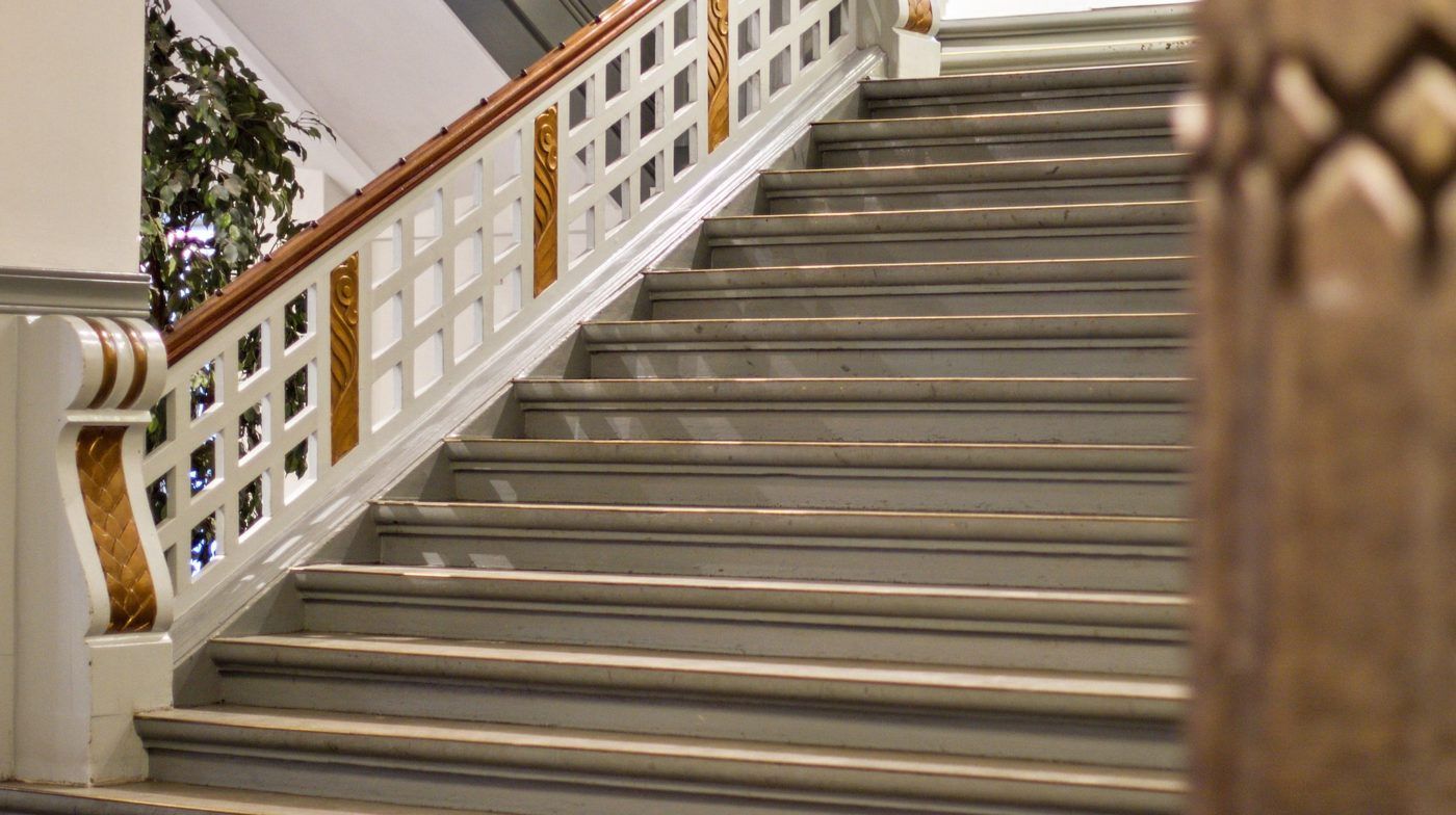 Sted med hvide og lysegrå marmortrapper og lysegrå, smukke udsmykninger i brun og guld. Sted med slanke, hvide søjler og