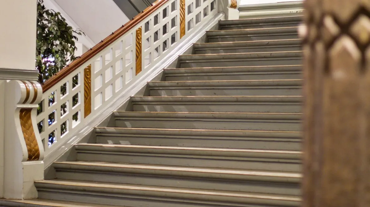 Sted med hvide og lysegrå marmortrapper og lysegrå, smukke udsmykninger i brun og guld. Sted med slanke, hvide søjler og