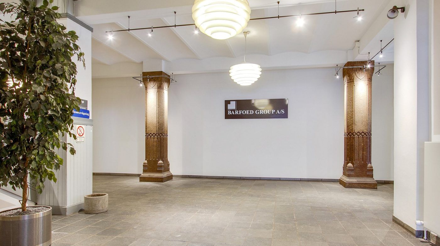 En stor hall med marmorgulv og tre lysekroner hængende fra loftet, sammen med to store kolonner og et skilt med teksten