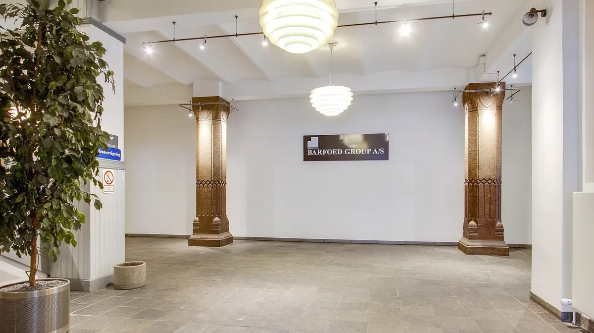 En stor hall med marmorgulv og tre lysekroner hængende fra loftet, sammen med to store kolonner og et skilt med teksten