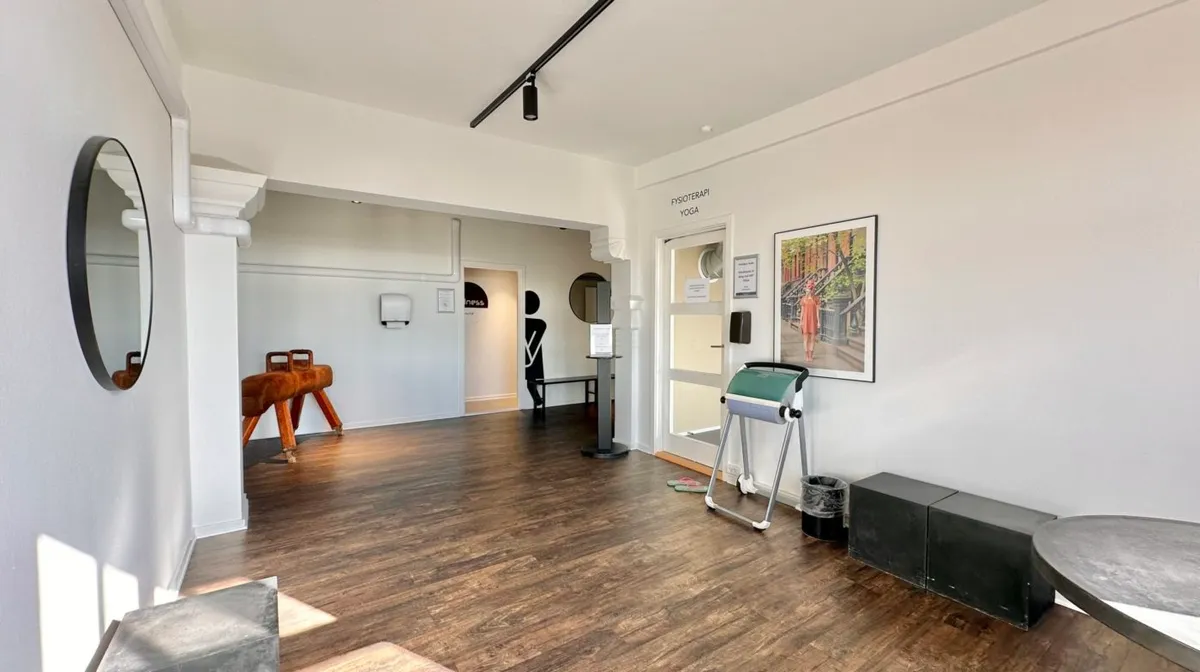 Forplejningsrum med trægulve og en simpel indretning, der inkluderer et rundt spejl og træborde