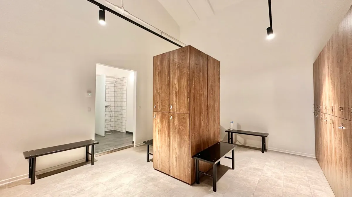 Store træskabe med metalhåndtag i et moderne omklædningsrum med hvid og brun farvelægning samt lysekroner