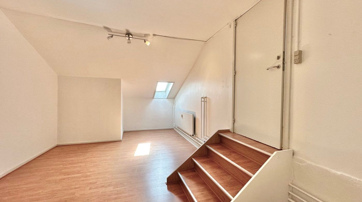 Lokaler med åbne lofter og vinduesindbygget lys. Sti med trætrin og hvid væg med dør og elektriske stikkontakter