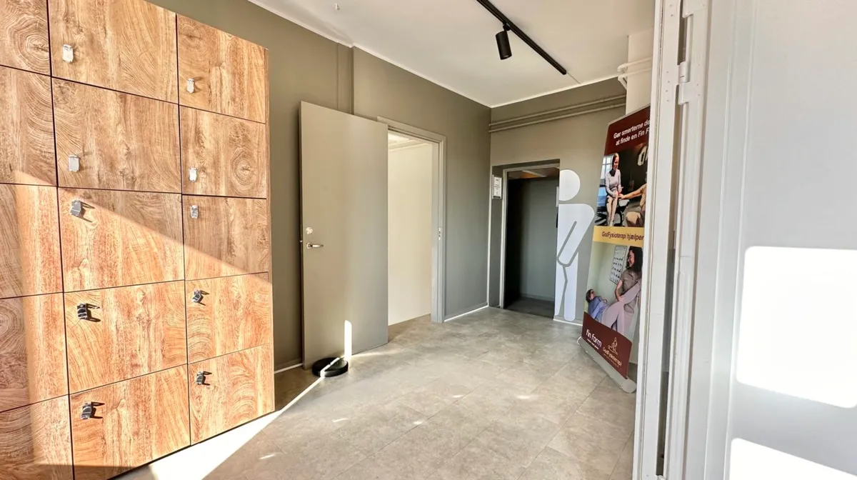 Hallen i FinForm Fitness med et moderne design, træskabe, højt gulv og tekst på skiltet