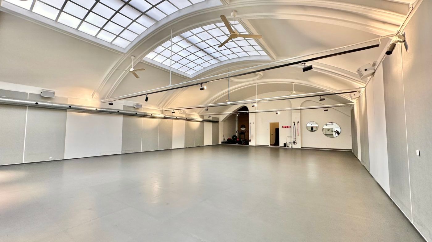 Moderne fitnesslokale med højt til loftet, to store ventilerede loftsventilatorer, en stor spejlvæg og en afsondret