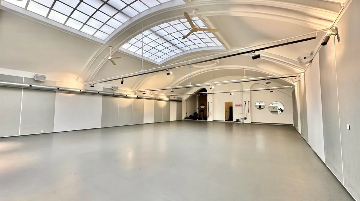 Moderne fitnesslokale med højt til loftet, to store ventilerede loftsventilatorer, en stor spejlvæg og en afsondret