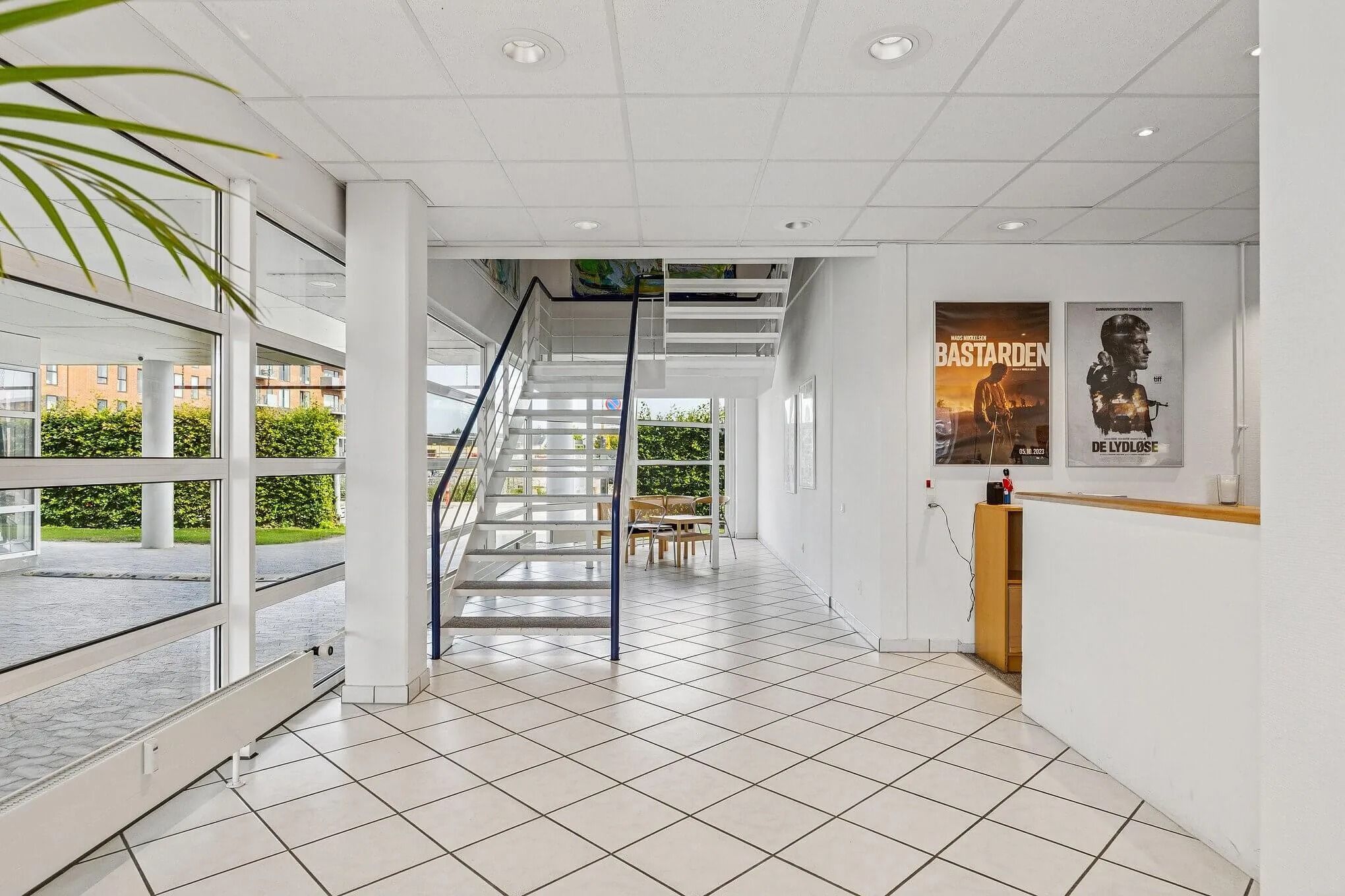 Kontor med åbne ruder og lyse lofter, skrivebord med lyse farver, høj kvalitet og glasvinduer samt plakater på væggen