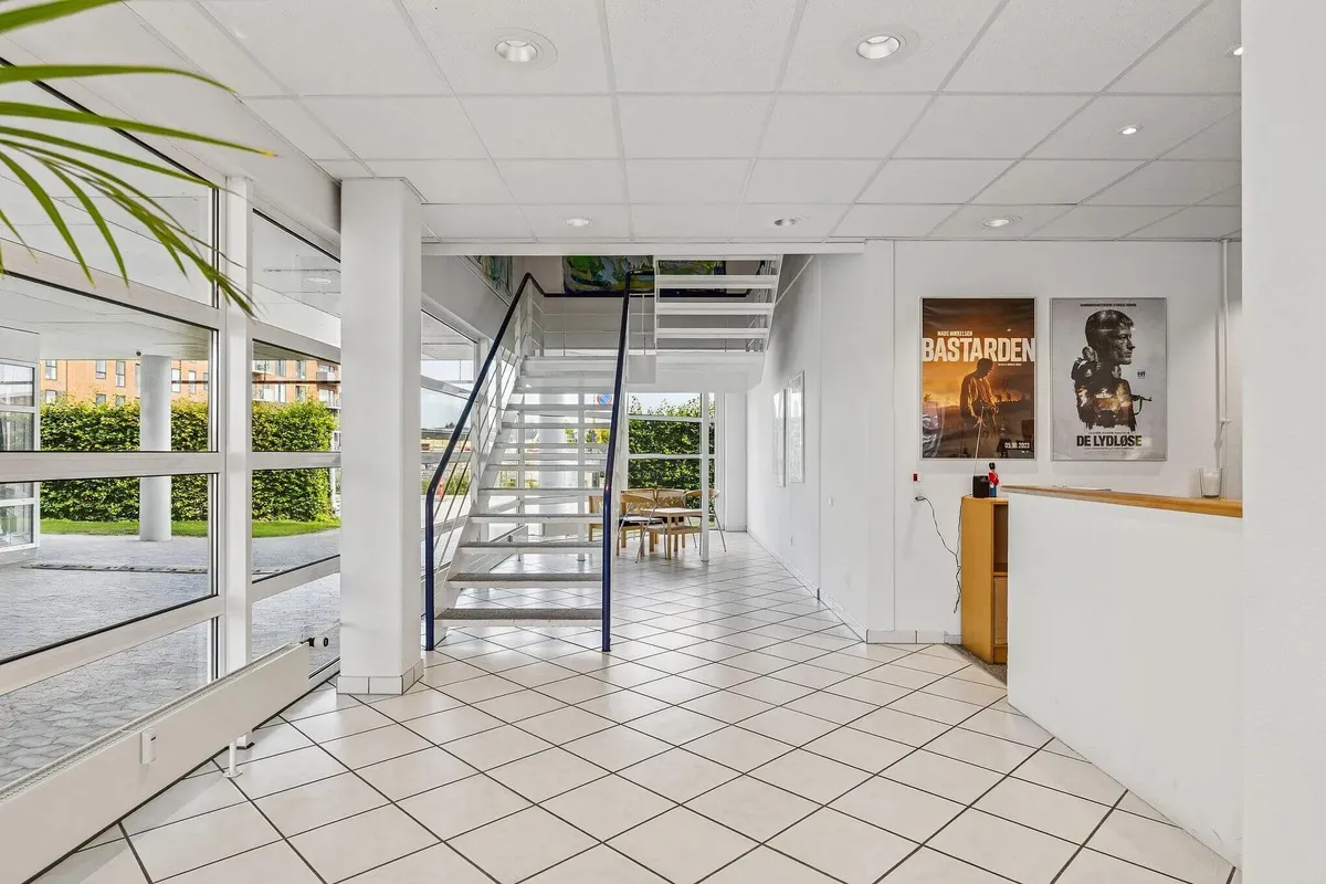 Kontor med åbne ruder og lyse lofter, skrivebord med lyse farver, høj kvalitet og glasvinduer samt plakater på væggen