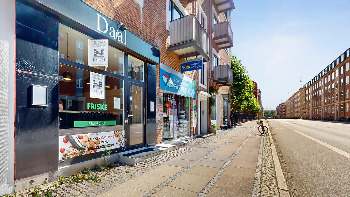 Bygning med skiltet Dalal, café med skiltet Friske Madbox, byggede i røde mursten og glasvinduer, bilparkering langs vejen,