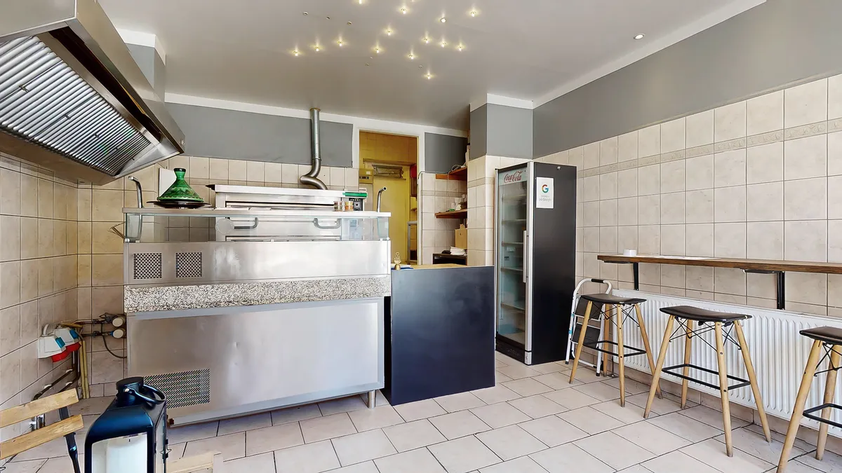 Et slankt og funktionelt køkken med moderne indretning, en indbygget ovn og en Coca-Cola køleskab